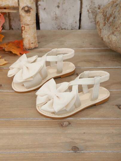 1 Pair Beige Infant/Toddler Girls' Flat Sandals, Solid Color Soft Fabric Criss-Cross Strap With Bow Decor, Classic Round Toe Open Toe Non-Slip Slip-On Design, Fashionable Cute Princess Style Beach/Casual Sandals For Spring/Summer