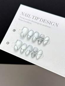 10片纯手工制作的按压式美甲贴片，短杏仁形，时尚简约风格，饰有手绘灰白色烟花猫眼效果、立体手绘银色花朵，并点缀不规则的手绘银镜粉线条和水钻装饰，是一款高端美甲贴片，适合女性和女孩日常佩戴，并附赠美甲套装。 - 彩色 - 查看 1