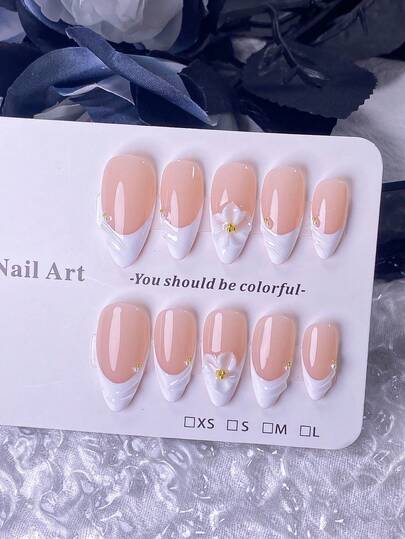 10 片手工杏仁形美甲贴片，饰以白色高位法式水波纹图案、精致设计、钢珠和珍珠。其特色在于手工雕刻的立体白色花卉图案，中心点缀着小钢珠。灵感源自春天，简约百搭，时尚高端。适合任何场合。快速佩戴和卸除；按压式美甲贴片。