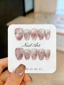 Bộ 10 móng giả ngắn hình hạnh nhân thủ công, được trang trí bằng hoa trắng 3D, kim cương giả, ngọc trai trắng, vảy xà cừ và hiệu ứng chuyển màu hồng không đều. Những bộ móng giả dễ thương này có thể tái sử dụng, dễ dàng dán và tháo gỡ, giúp làm sáng và thon gọn bàn tay. Thích hợp cho phụ nữ và các cô gái dự tiệc, đám cưới, sử dụng hàng ngày và tự làm móng. Đi kèm với bộ dụng cụ. Móng giả thủ công, dụng cụ làm móng. - Màu Hồng baby - Xem 10