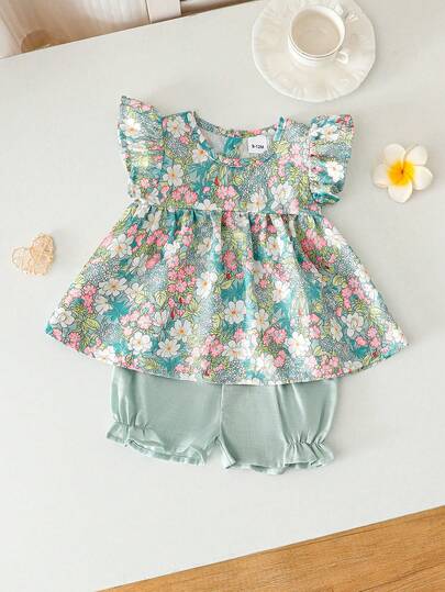 Bộ đồ hè 2 món cho bé gái: Áo hai dây bèo nhún họa tiết hoa + Quần short ống rộng màu xanh nhạt, thiết kế đồng quê tươi mát.