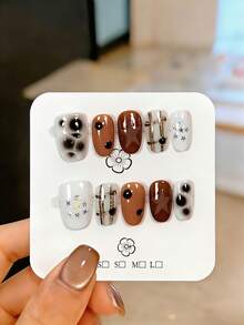 10片手工制作的短款按压式假指甲，饰有不规则黑色墨点、银色五角星图案、闪粉点缀和深棕色格子渐变效果。这些可爱的假指甲可重复使用，易于佩戴和卸除，能够提亮并修饰手部线条，使双手看起来更纤细。适合女性和女孩在派对、婚礼、日常佩戴和DIY美甲时使用。附赠工具包。手工指甲贴片、假指甲、美甲用品。 - 白色 - 查看 11