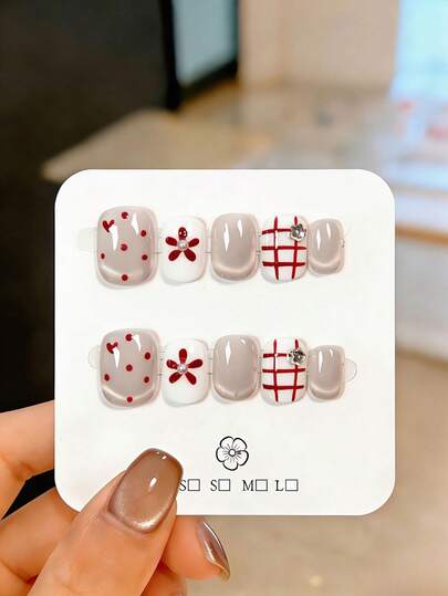 10片手工制作的短款按压式假指甲，采用银白色猫眼造型，饰以手绘红色波点爱心图案、花卉纹样和不规则线条。这些可爱漂亮的假指甲可重复使用，易于佩戴和卸除。它们可以修饰手部线条，提亮手部外观，适合女性和女孩在派对、婚礼、日常佩戴和DIY美甲时使用。附赠工具包。手工指甲贴片、假指甲、美甲用品。