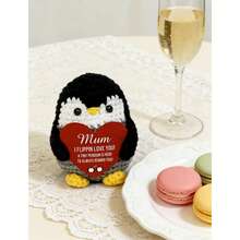 1个手工钩织圆形企鹅摆件，手捧一张鲜红色的心形卡片，卡片上印着“妈妈，我爱你”和“小企鹅永远在你身边”。设计柔软可爱，饱含温暖人心的情感，触动每一位母亲的心。 - 彩色 - 查看 5