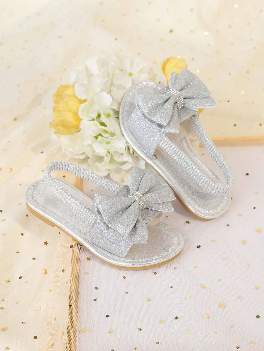 1 đôi dép xăng đan đế bằng màu bạc cỡ lớn dành cho bé gái, chất liệu PU mềm mại, bóng bẩy, trang trí nơ lớn, quai hậu co giãn, mũi tròn, đế chống trượt thoải mái, kiểu dép La Mã thời trang, thanh lịch và dễ thương, phù hợp cho bé gái từ 3-15 tuổi đi hàng ngày, dự tiệc, du lịch, mùa xuân/hè 2026. - Bạc - Xem 1