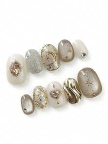 这款美甲套装包含10片指甲油，名为“金沙月心”。它巧妙地融合了闪耀的香槟色和乳白色，金色的星星和宝石细节在柔和的底色上熠熠生辉，宛如繁星点缀在金色的沙滩上。波浪状的液态金属装饰更添一丝俏皮奢华，营造出梦幻般的怀旧氛围。 - 彩色 - 查看 2