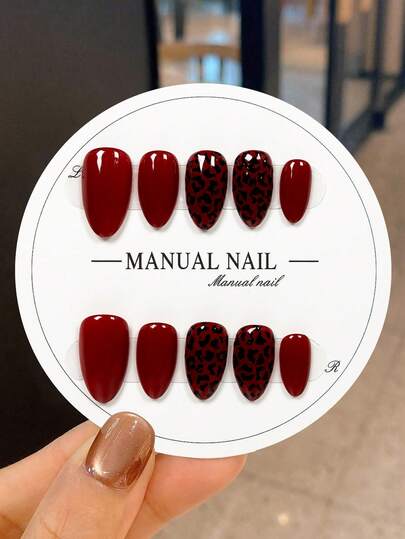 JUTI 10片手工制作的短款杏仁形美甲贴纸，纯正的酒红色，打造大胆性感的造型，饰以手绘黑色豹纹，更添前卫吸睛的魅力。每片贴纸均为100%纯手工绘制和制作，展现出狂野迷人的美甲风格。这款美甲贴纸兼具经典、时尚和高品质的美感，适合成熟和年轻的各种风格，适用于任何场合，并且易于卸除。