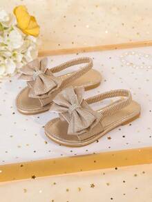 1 đôi sandal đế bằng màu vàng kim cỡ lớn dành cho bé gái, chất liệu PU mềm mại, bóng bẩy, trang trí nơ lớn, quai đeo mắt cá chân co giãn, mũi tròn, đế chống trượt thoải mái, kiểu sandal La Mã thời trang, thanh lịch, dễ thương phù hợp cho bé gái từ 3-15 tuổi, dùng hàng ngày, dự tiệc, du lịch, mùa xuân/hè 2026. - Hoa hồng vàng - Xem 2