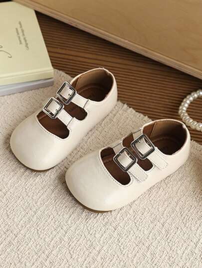 1双儿童米色软皮鞋底+圆形镂空鞋面+双搭扣+金属扣+平跟+简约温柔风格女童鞋，适合2026年夏季日常穿着、上学和家庭郊游。