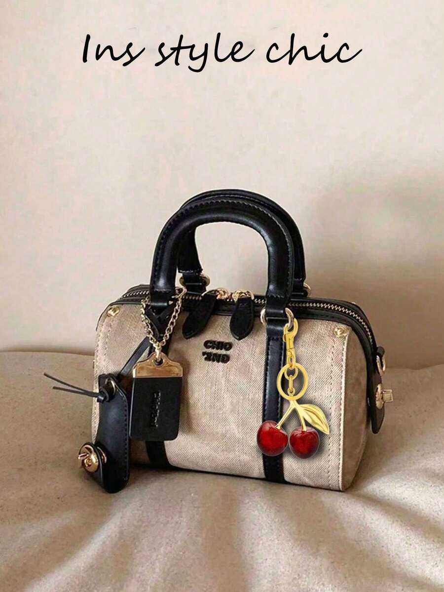 这款时尚新款女士半哑光摩卡色枕形手提包采用PU材质，配有可调节肩带，饰以金属吊坠和标签，以及一颗红色樱桃吊坠点缀。这是一款优雅的手提包/斜挎包，品质高端，适合办公通勤、聚会、购物等各种场合。 - 黑色 - 查看 1