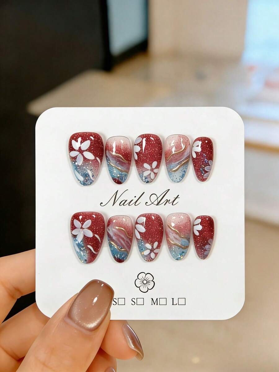 10片手工制作的短款杏仁形按压式假指甲，多处镶嵌银蓝色闪粉和碎钻，饰以金色线条、手绘白色五瓣花图案和酒红色渐变效果。这些可爱漂亮的假指甲可重复使用，易于佩戴和卸除，是优雅的美甲装饰。适合女孩和女士日常佩戴，也适用于派对、婚礼和节日美甲。套装包含美甲工具，如果冻胶和指甲锉。 - 紅色 - 查看 1