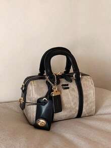 这款时尚新款女士半哑光摩卡色枕形手提包采用PU材质，配有可调节肩带，饰以金属吊坠和标签，以及一颗红色樱桃吊坠点缀。这是一款优雅的手提包/斜挎包，品质高端，适合办公通勤、聚会、购物等各种场合。 - 黑色 - 查看 4