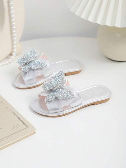 Dép xăng đan đế bằng màu bạc cho bé gái, chất liệu da mềm mại đính sequin, trang trí hình bướm đính đá nhiều màu sắc, mũi tròn, đế mềm chống trơn trượt, kiểu dáng xỏ chân tiện lợi, phong cách công chúa thời trang thích hợp cho đi biển/nghỉ lễ/đi học, phù hợp cho bé gái từ 3-12 tuổi, bộ sưu tập Xuân/Hè 2026.