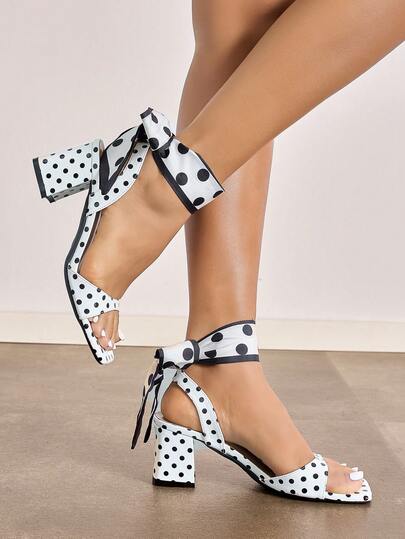 女士高跟鞋，适合派对、户外活动、旅行、舞台表演和正式场合。特点包括：深色粗跟、方头、收腰设计、穆勒鞋款式、绑带、波点围巾式腿套。采用优质镜面材质，舒适优雅，白色可选。