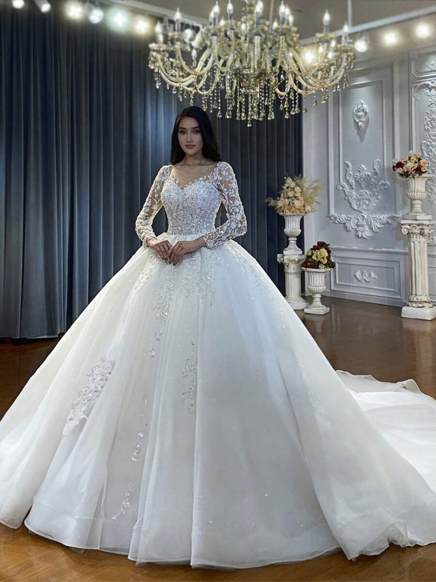Luxury Long Sleeve V-Neck Ball Gown Wedding Dress With Crystal Beading, Tulle Skirt, And Cathedral Train – Premium Lace And Tulle With Hand-Applied Crystal Embellishments, Fitted Bodice With Boning, V-Neckline With Illusion Lace, Cathedral Train With Lace Edging, Available In Ivory – Perfect For Fall/Winter Indoor Weddings, Palace Ceremonies, And Destination Weddings, Warm And Elegant Design, Ideal For Cooler Weather, International Export Quality, Suitable For Global Bridal Market - trắng - Xem 1