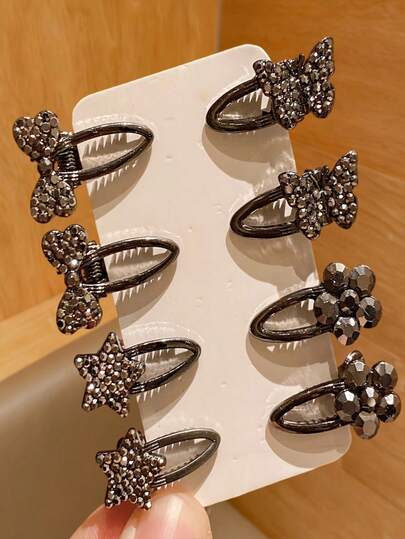 8个黑色亮面迷你发夹，款式多样，包括蝴蝶、星星、花朵和蝴蝶结，适合刘海和额头造型。