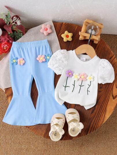 Bộ đồ 2 món cho bé gái gồm áo tay ngắn và quần ống loe màu trắng dệt kim họa tiết hoa, chất liệu nhẹ, thích hợp cho mùa xuân/hè.