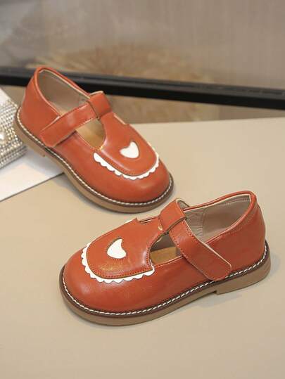 Đôi giày lười màu nâu cam với mũi giày khoét hình trái tim màu trắng và dây buộc lượn sóng mang đậm phong cách công chúa, có thể mang được trong mọi mùa. Là món đồ yêu thích của trẻ em, phù hợp cho việc đi học hàng ngày, tiệc sinh nhật, biểu diễn văn hóa, vui chơi và các dịp khác.