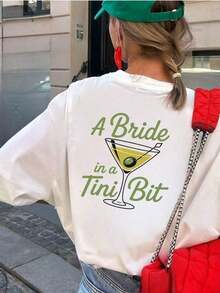 Camiseta Gráfica Oversized para Mujer 100% Algodón - Blanca, de Manga Corta, con Texto Divertido "A Bride In A Tini Bit" y Estampado de Copa de Martini. Top de algodón suave de corte holgado, perfecto para despedidas de soltera, fiestas de novias, viajes de chicas y eventos previos al matrimonio. Camiseta popular con temática nupcial, de corte cómodo y relajado, ideal para futuras novias y miembros del cortejo nupcial. - Blanco - Ver 3