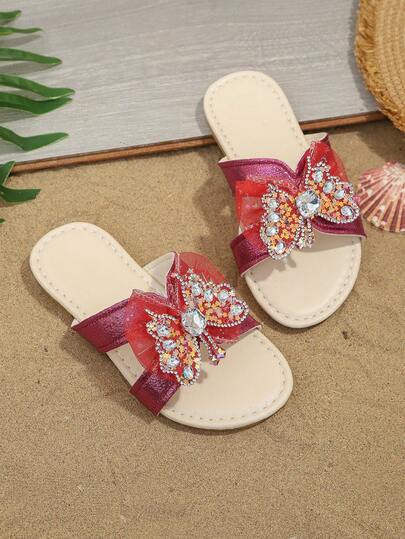 1双玫红色加大码女童时尚拖鞋，闪亮水晶搭扣和网纱蝴蝶装饰，圆头柔软防滑一脚蹬设计，别致波西米亚公主风沙滩凉鞋，适合休闲、度假、派对、春夏穿着。