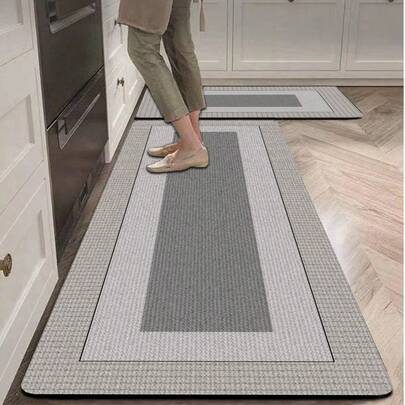 1 tấm thảm trải sàn nhà bếp bằng gel silica, với thiết kế họa tiết hình học ba lớp lồng nhau: Lớp ngoài cùng là họa tiết sọc dọc mịn màu xám nhạt, lớp giữa là vùng màu xám nhạt mịn, và trung tâm là vùng hình chữ nhật đặc màu xám đậm. Tổng thể có tông màu nhẹ nhàng và nhiều lớp, mang phong cách tối giản và thanh lịch. Thích hợp cho nhà bếp, phòng tắm, lối vào, phòng giặt, phòng ngủ, phòng khách và các không gian trang trí khác.