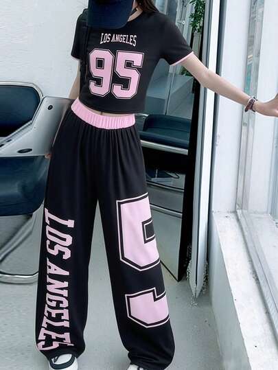 两件套女童休闲运动套装，包括一件印有英文字母和数字的圆领短袖上衣，以及一条黑粉拼接腰带短裤。这套英文字母+数字印花套装非常适合女孩们日常穿着、运动、郊游、聚会、度假以及夏季户外活动。