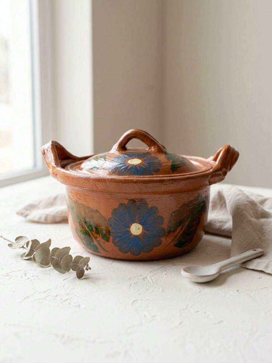 Forma cilíndrica, asas laterales, tapa abombada, decorado floral. Esta olla es perfecta para la preparación y presentación de platillos tradicionales como guisos, sopas, frijoles o caldos tanto en comidas diarias como en celebraciones familiares, fiestas o eventos donde se quiera resaltar la cocina casera y la cultura gastronómica. - Ver 1
