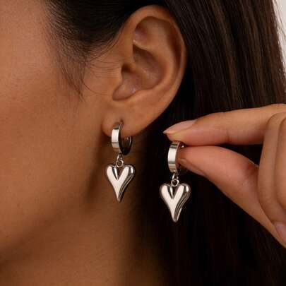 Un par de pendientes de diseño exclusivo para mujer con colgantes de corazón tridimensionales dorados y aro de clip, adecuados para el uso diario de las mujeres