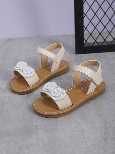 1 đôi sandal thời trang cho bé gái, màu trắng ngà, quai vải mềm mại, điểm nhấn là nơ đôi đính ngọc trai lấp lánh, mũi tròn, đế mềm chống trơn trượt, thiết kế quai ngang, phong cách bohemian thời trang đi biển, phù hợp cho sinh hoạt hàng ngày, lễ hội và các buổi tụ họp, hàng mới về mùa xuân/hè.