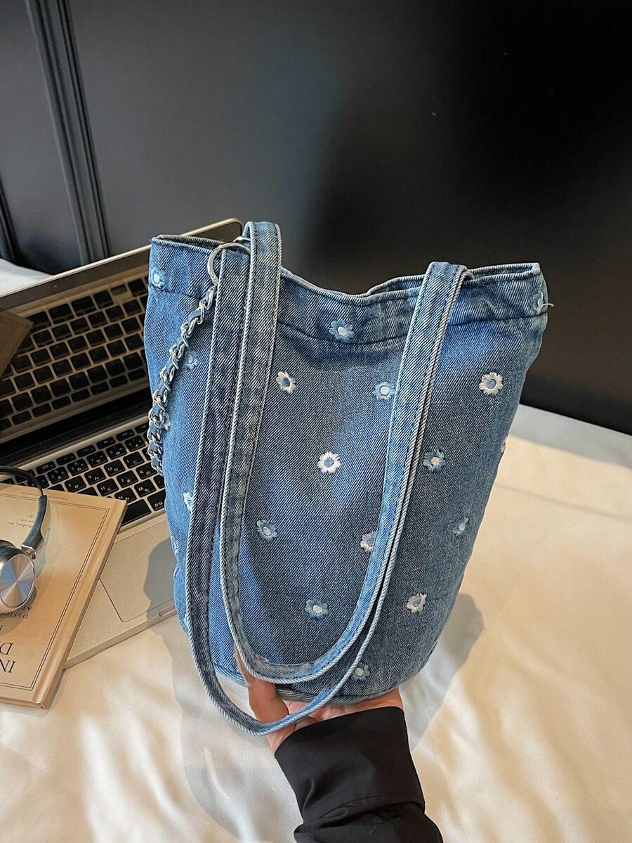 Bolsa de tecido jeans multicolorida azul com bordado de margaridas e corrente metálica, estilo tote, transversal ou para usar no ombro. Fecho de pressão. Design moderno e delicado, ideal para o dia a dia, deslocamentos, escola e compras.