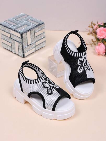 1 đôi dép xăng đan cao gót mùa hè cho trẻ em, phần trên bằng vải phối màu đen trắng với họa tiết bướm, thiết kế xỏ chân tiện lợi với lỗ thoáng khí, dép xăng đan thời trang cho bé gái, phù hợp cho các hoạt động hàng ngày như đi chơi, mua sắm, dự tiệc và các hoạt động trên bãi biển.