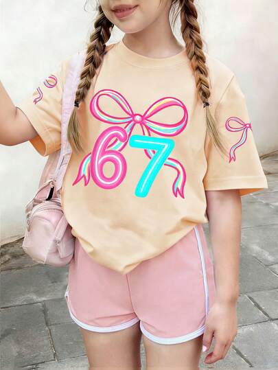 This Light Apricot Round Neck T-Shirt Is Designed For Girls, Printed With A Creative Blue Bow And The Number "67", Very Suitable For Young Girls To Wear. It Is Suitable For School, Shopping, Daily Wear And Vacation Occasions.