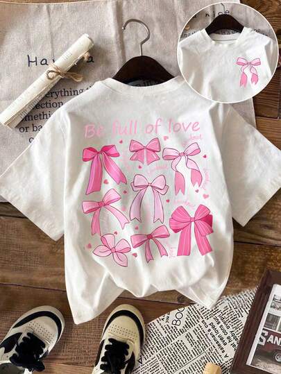 Áo thun trắng cỡ lớn dễ thương với họa tiết nơ hồng, tay ngắn, cổ tròn, chất liệu co giãn cao, dáng suông, tạo nên vẻ ngoài ngọt ngào.