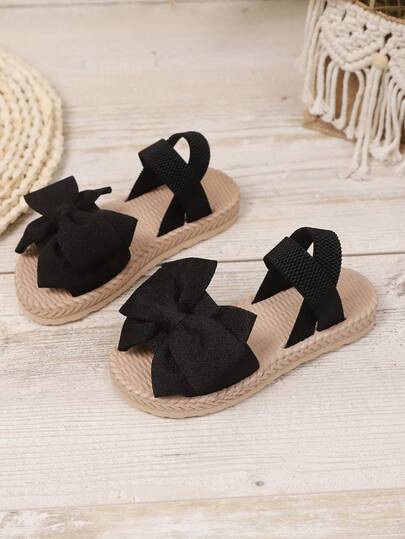 1双婴幼儿女童平底凉鞋，舒适柔软的黑色面料，饰有大蝴蝶结，圆头露趾设计，弹性柔软鞋底，加高鞋跟，弹性面料套穿式设计，时尚波西米亚风沙滩凉鞋，适合日常休闲、度假、上学等场合，春夏新品上市。