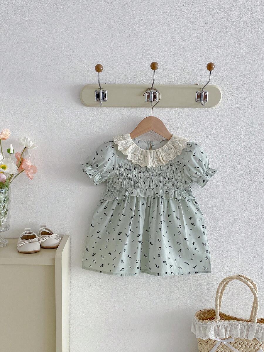 1 chiếc đầm hè cho bé gái màu xanh lá nhạt họa tiết hoa nhí, đầm xếp ly cổ ren/tay phồng kiểu công chúa, dáng rộng nhẹ.