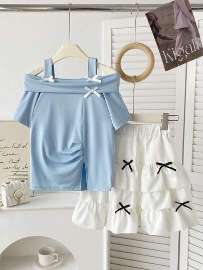 Bộ đồ mùa hè thường ngày cho bé gái: áo hai dây màu xanh trơn có nơ và chân váy ngắn màu trắng.