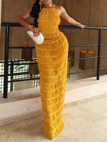 Este conjunto de férias feminino, composto por camisola sem costas e saia maxi, é feito de chiffon jacquard, com bainhas franzidas e detalhes em renda sobreposta. O design com alças finas é a escolha ideal para um look de férias na praia. Verão