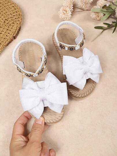 1 Đôi dép xăng đan đế dày màu trắng cỡ lớn dành cho bé gái, chất liệu vải mềm mại, màu trơn với nơ lớn, kiểu dáng xỏ chân co giãn, trang trí hoa vàng đơn giản, thiết kế mũi tròn cổ điển, đế mềm co giãn, dép xăng đan đế dày thời trang và dễ thương, phù hợp cho bé gái từ 3-15 tuổi đi hàng ngày, đi chơi, dự tiệc, du lịch, mẫu mới mùa xuân/hè.