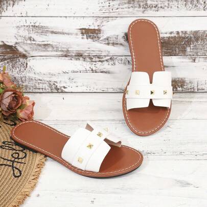 Sandal đế bằng nữ, đính đinh tán, kiểu dáng slip-on, quai chéo, thích hợp cho kỳ nghỉ.