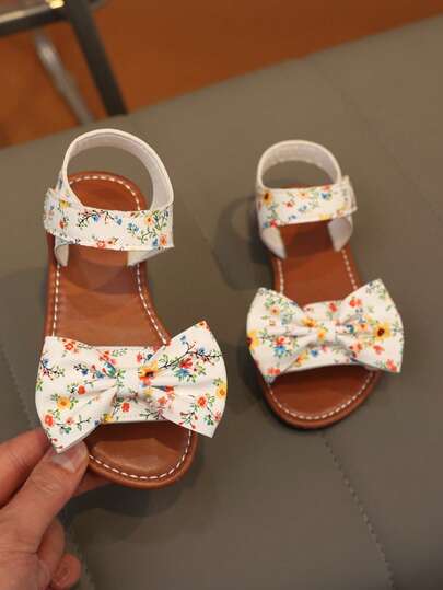 1 đôi dép xăng đan PU cho bé gái, trang trí nơ hoa, đế mềm chống trượt, chống mài mòn, thiết kế hở mũi, gót thấp bằng phẳng có khóa dán, kiểu dáng ngọt ngào, tươi tắn, dép trẻ em thích hợp mang hàng ngày, ngoài trời, đi biển, mùa hè, thoáng khí và thoải mái.