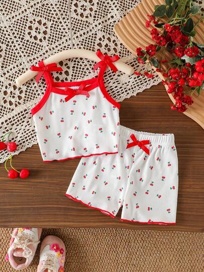 Bộ đồ 2 món cho bé gái, gồm áo hai dây và quần short in hình quả anh đào dễ thương kèm nơ, thích hợp cho mùa hè.