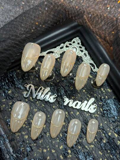 10片杏仁美甲亚克力套装，杏色指甲，手绘金色细线从指甲表面下半部分向外辐射，设计类似法式断续菱形线条，视觉上拉长指甲形状。