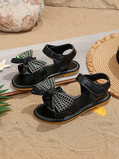 1 đôi dép xăng đan đế bằng màu đen mềm mại và thoải mái cho bé gái, trang trí nơ nhiều màu sắc, có khóa cài, mũi tròn, đế mềm chống trượt, giày đi biển công chúa phong cách Bohemian thời trang, thích hợp cho đi hàng ngày, đi nghỉ mát, dự tiệc, mùa xuân/hè 2026.