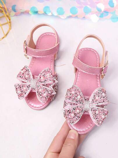 2026 Nuevas sandalias de princesa con doble lazo y rhinestones para niñas, suela suave de PU brillante con perlas, diseño de slip-on de punta abierta, adecuadas para uso diario/actuaciones en el escenario