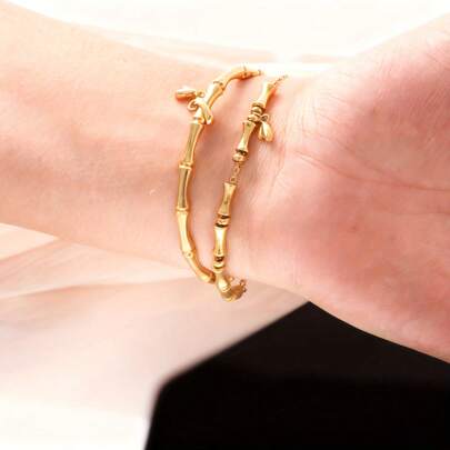 Vòng tay hai lớp bằng thép không gỉ mạ vàng 18K hình nút tre với mặt dây chuyền hình lá tre, phụ kiện phong cách Trung Hoa thanh lịch, phù hợp cho việc đi lại hàng ngày, phối cùng trang phục lấy cảm hứng từ Trung Hoa và là món quà ý nghĩa dành cho quý cô chu đáo.