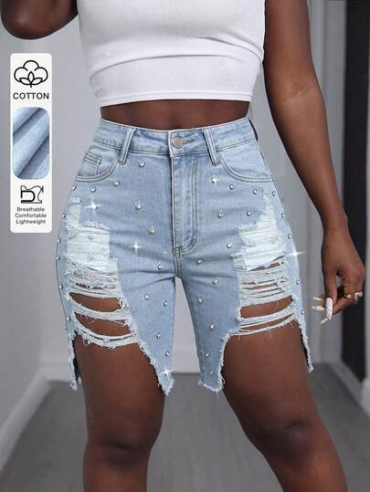 Quần short denim nữ phong cách đường phố, thiết kế ống đứng thoải mái, trang trí bằng các chi tiết rách, đinh tán và túi, màu xanh nhạt, độ co giãn vừa phải, chiều dài ngắn, tạo nên vẻ ngoài thời trang.