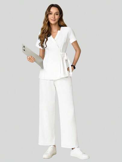 cimmuovere Dames scrubset bestaande uit een top met V-hals, korte mouwen, zakken en een gedraaide voorkant, en een broek met effen zakken. Geschikt voor schoonheidssalons, wellnesscentra, professionele kleding, verpleegkundigen, tandartsen, zorginstellingen, dierenklinieken en laboratoria. Witte lente