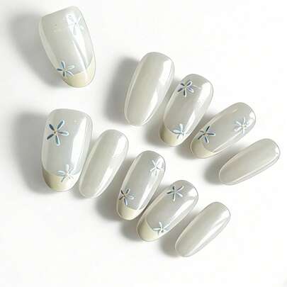 这款10片装美甲贴片采用柔和的半透明乳白色调，搭配经典的法式甲尖，并饰以精致的虹彩极光蓝花朵图案，散发出空灵柔美的仙气。高光泽的亮泽效果和修长的椭圆形甲型，打造出纤细优雅的手部线条。这款百搭美甲贴片，无论是日常妆容还是正式场合，都能轻松提升整体造型，是通勤、约会、婚礼和优雅聚会的理想之选。