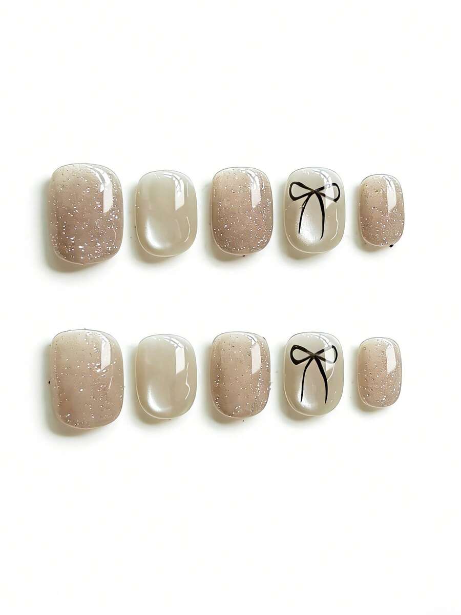 10pcs It Features An Elegant Palette Of Shimmering Nude Beige And Creamy Ivory, Adorned With Delicate Hand-Drawn Black Bow Motifs And Subtle Silver Glitter Accents, Exuding A Gentle And Sophisticated Vibe. The High-Shine Glossy Finish And Short Square Shape Create A Sleek, Versatile Daily Texture That Complements Any Outfit. Press On Nails - Apricot - View 1