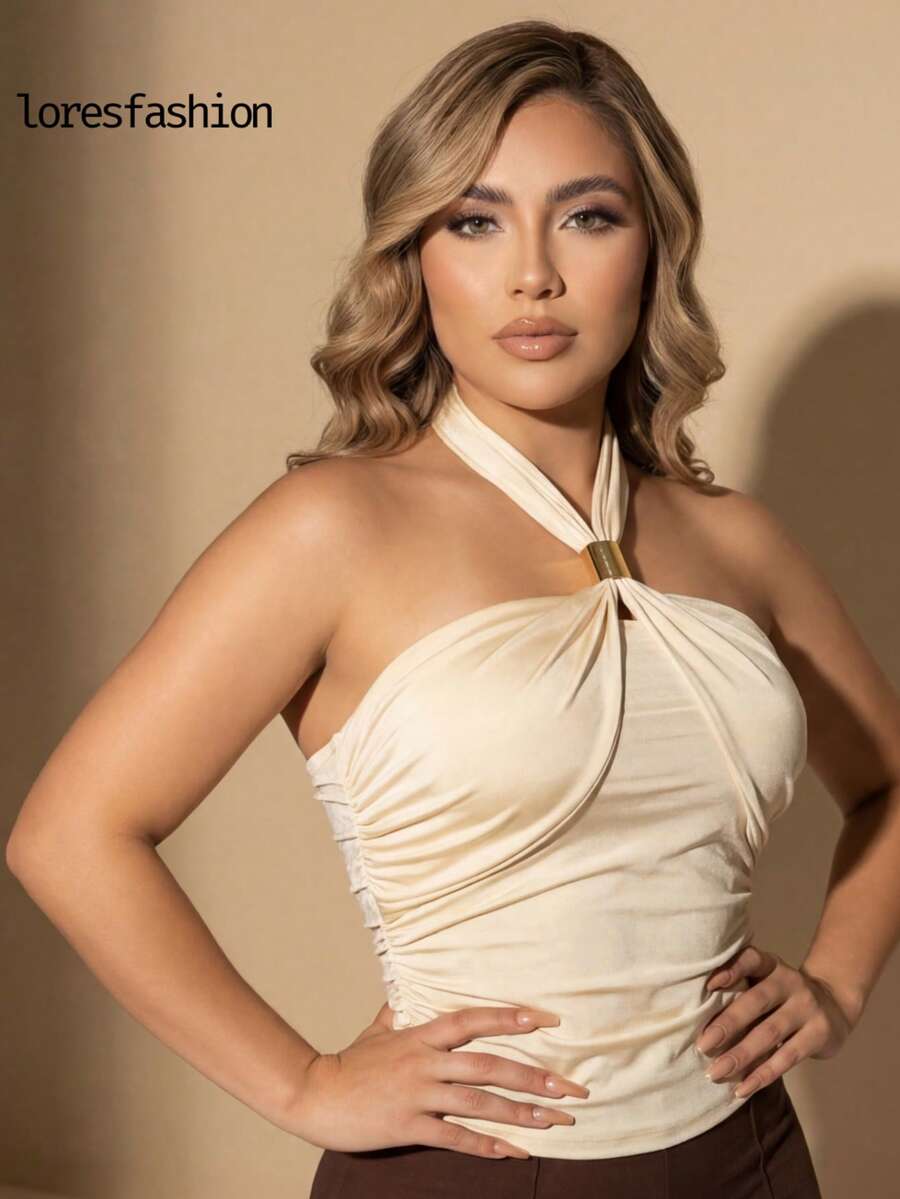 blusa asimetrica   elegante de cuello halter cruzado para mujer  , confeccionado en licra satinada stretch de alta calidad con textura sedosa, brillo sutil y ajuste perfecto que realza la figura; escote drapeado cruzado con frunces suaves que aportan un toque femenino y sofisticado, complementado con un herraje dorado central que añade distinción y elegancia; diseño con pliegues laterales que estilizan la cintura y crean una silueta armónica; espalda descubierta tipo strapless con acabado limpio